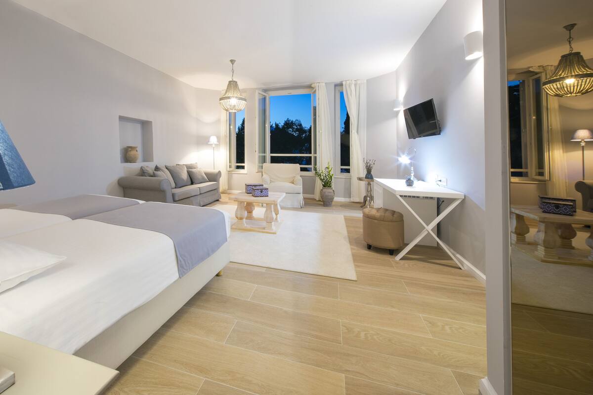 Quarto de hotel moderno com uma cama grande, uma mesa de escritório e um espaço de estar.