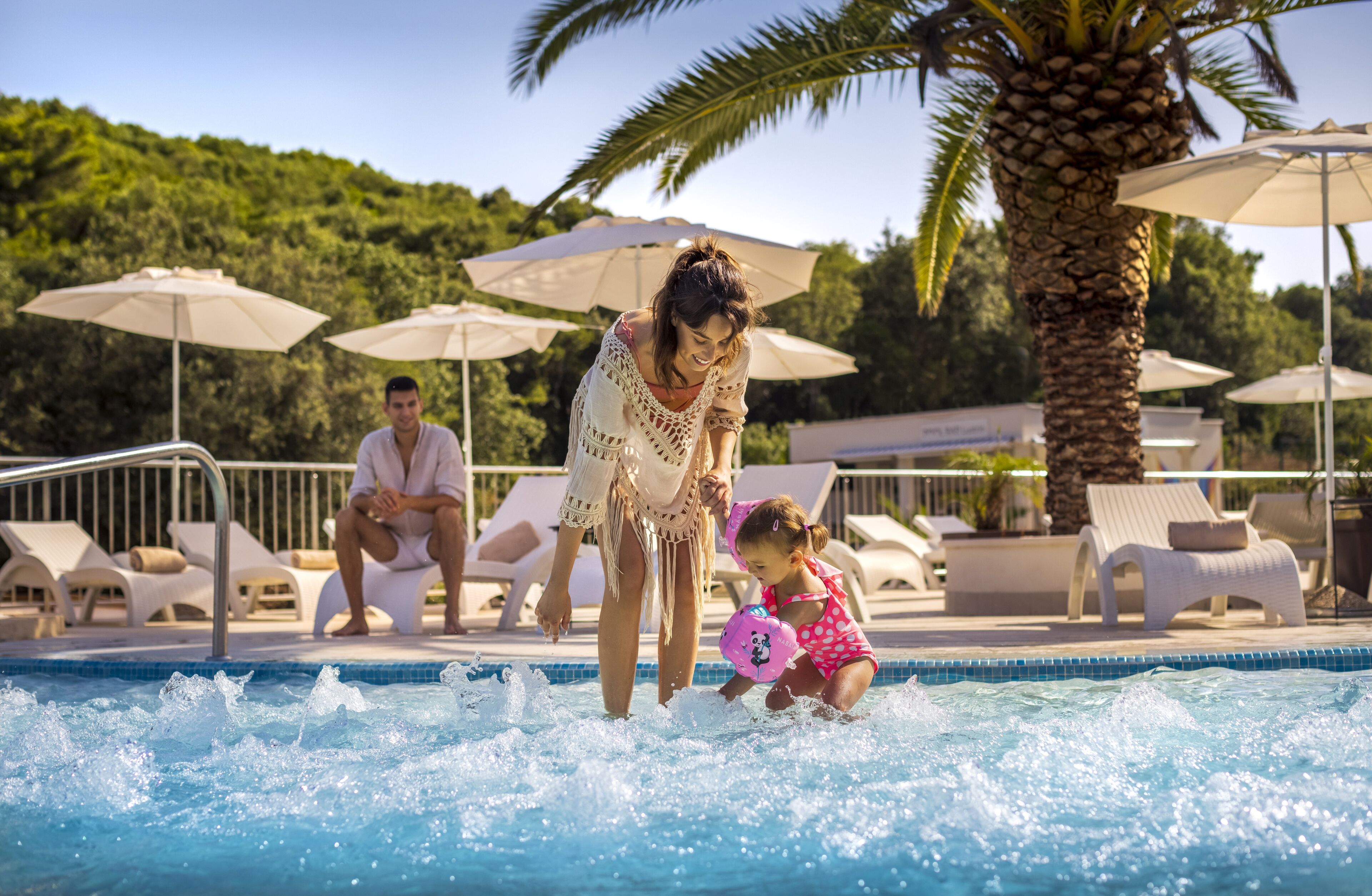 A pool area with lounge chairs and umbrellas.