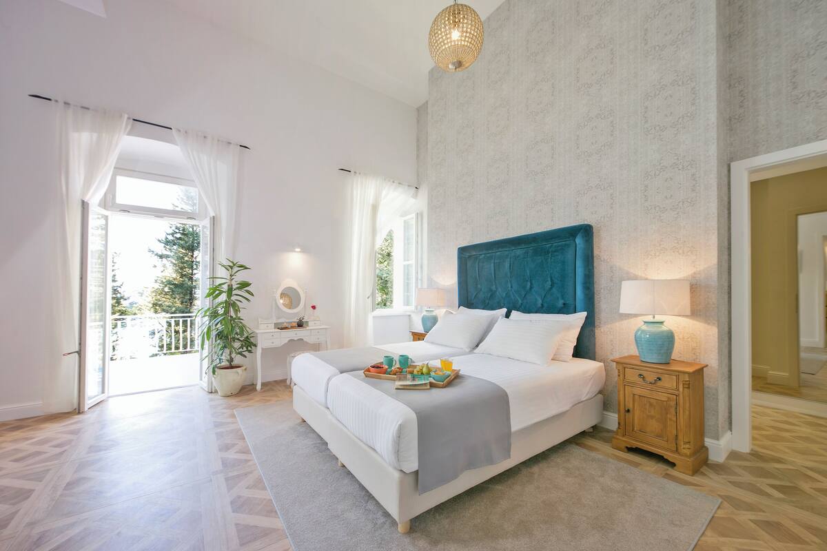 Quarto com uma cama grande, mesa de cabeceira, luminária pendente e vista para o exterior.