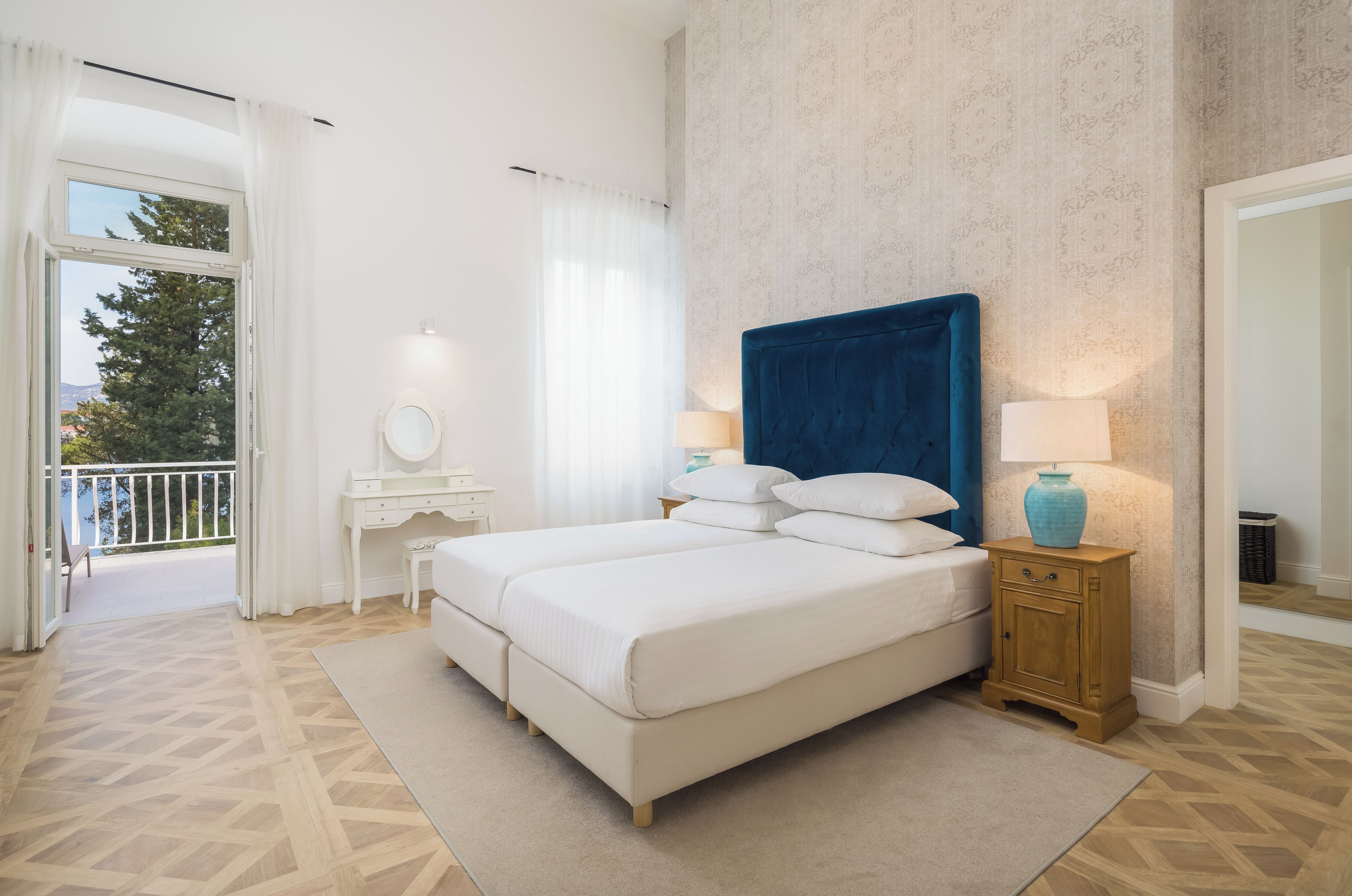 Une chambre à coucher avec un grand lit, une table de chevet, une commode et une vue sur l’extérieur.