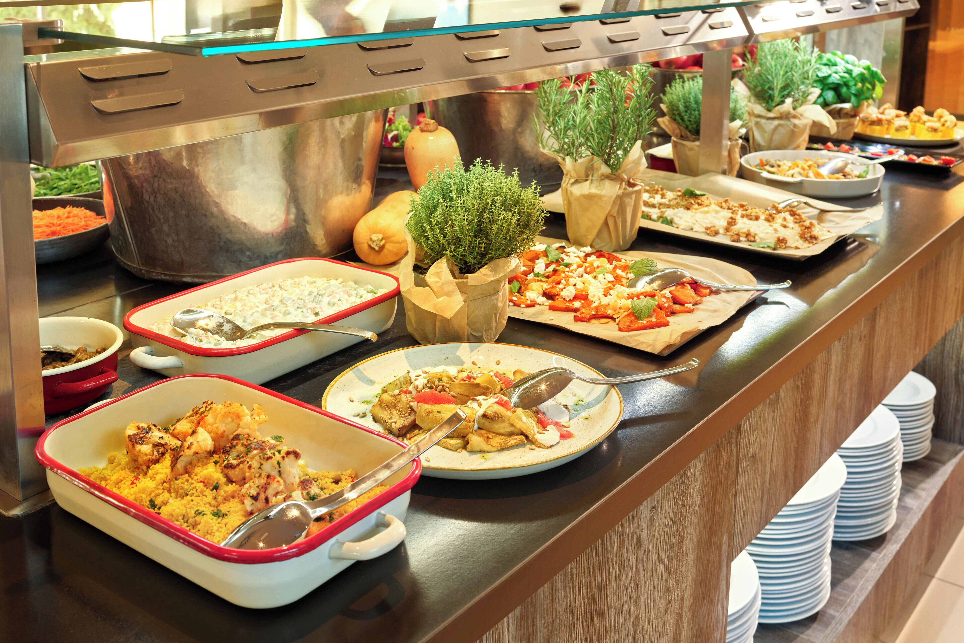 A buffet with various dishes, including salads, pasta, and a casserole.