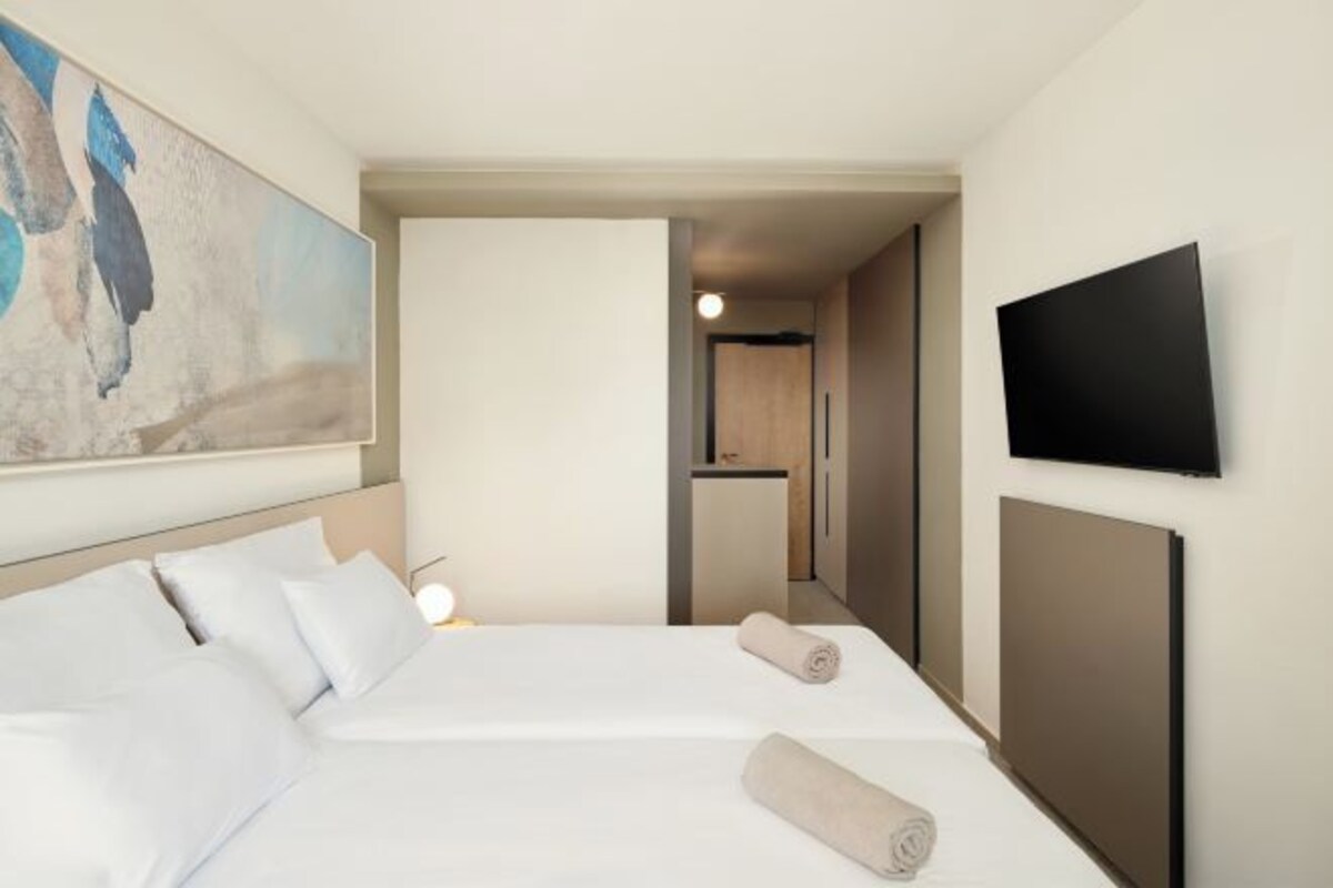 Una habitación de hotel con una cama, un televisor y un cuadro en la pared.