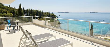 Un balcon équipé de deux chaises longues, d’une table et de chaises.