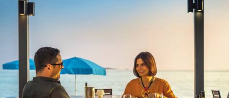 A couple dining at a table with a view of the sea.