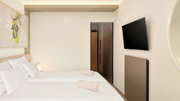 A hotel room with a bed, pillows, a flat-screen TV, and a painting on the wall.