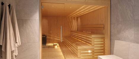 Una sauna con bancos de madera y una puerta de vidrio, frente a una pared revestida con azulejos.