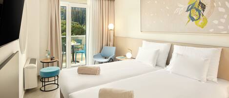 A hotel room with two beds, a TV, a desk with a chair, and a balcony with a table and chairs.