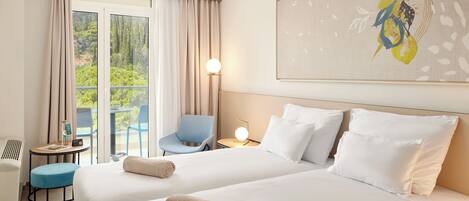 A hotel room with two beds, a desk, a chair, and a window with curtains.