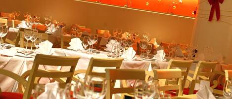 A restaurant with multiple tables set for dining, each with wine glasses and cutlery.