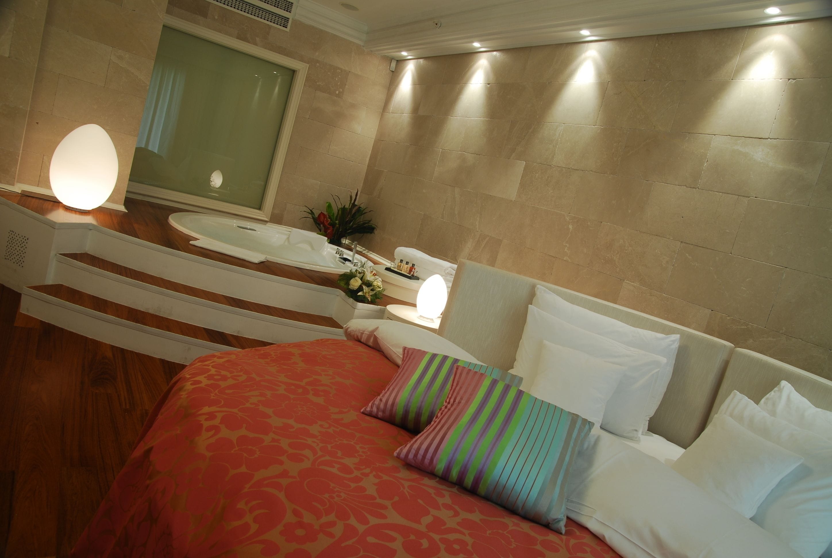 Habitación de hotel con cama, un espejo grande, un lavabo y ducha.