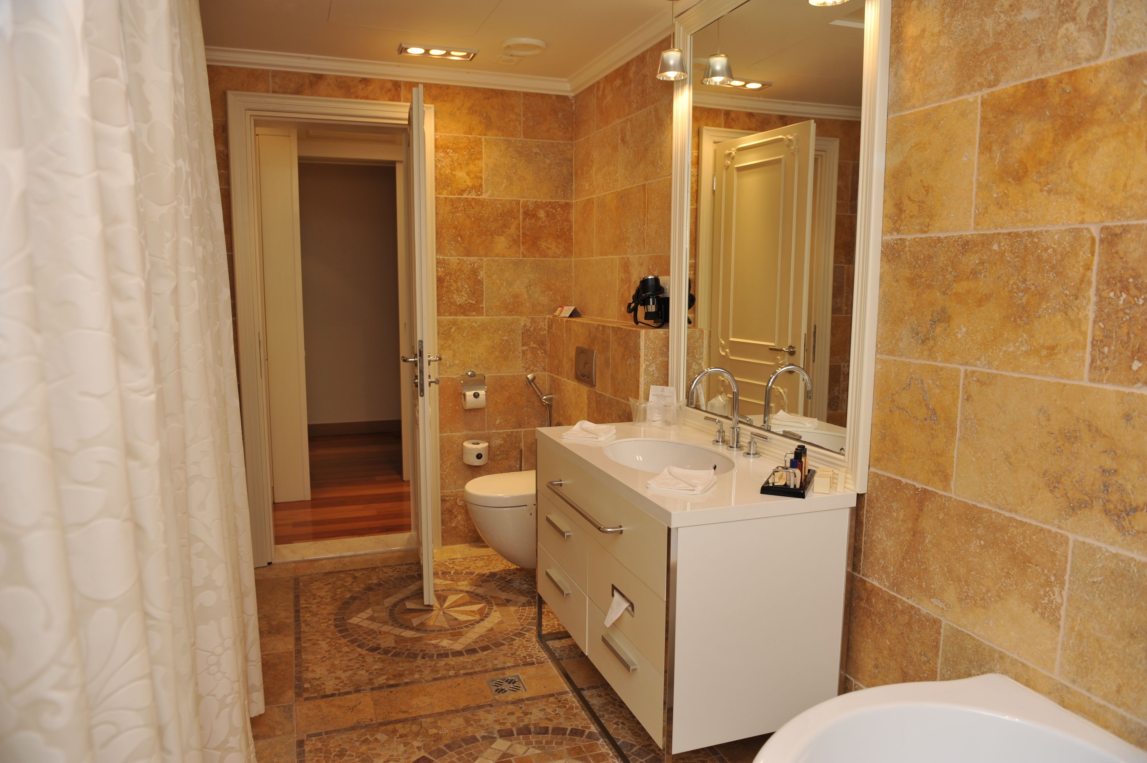 A bathroom with a double sink, toilet, and a shower area.