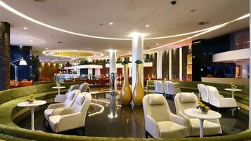 Un lobby moderno con una zona de estar curva, un bar y una recepción.