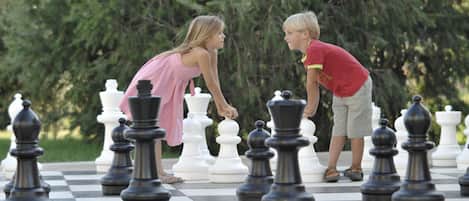 A chessboard with large chess pieces in a park setting.