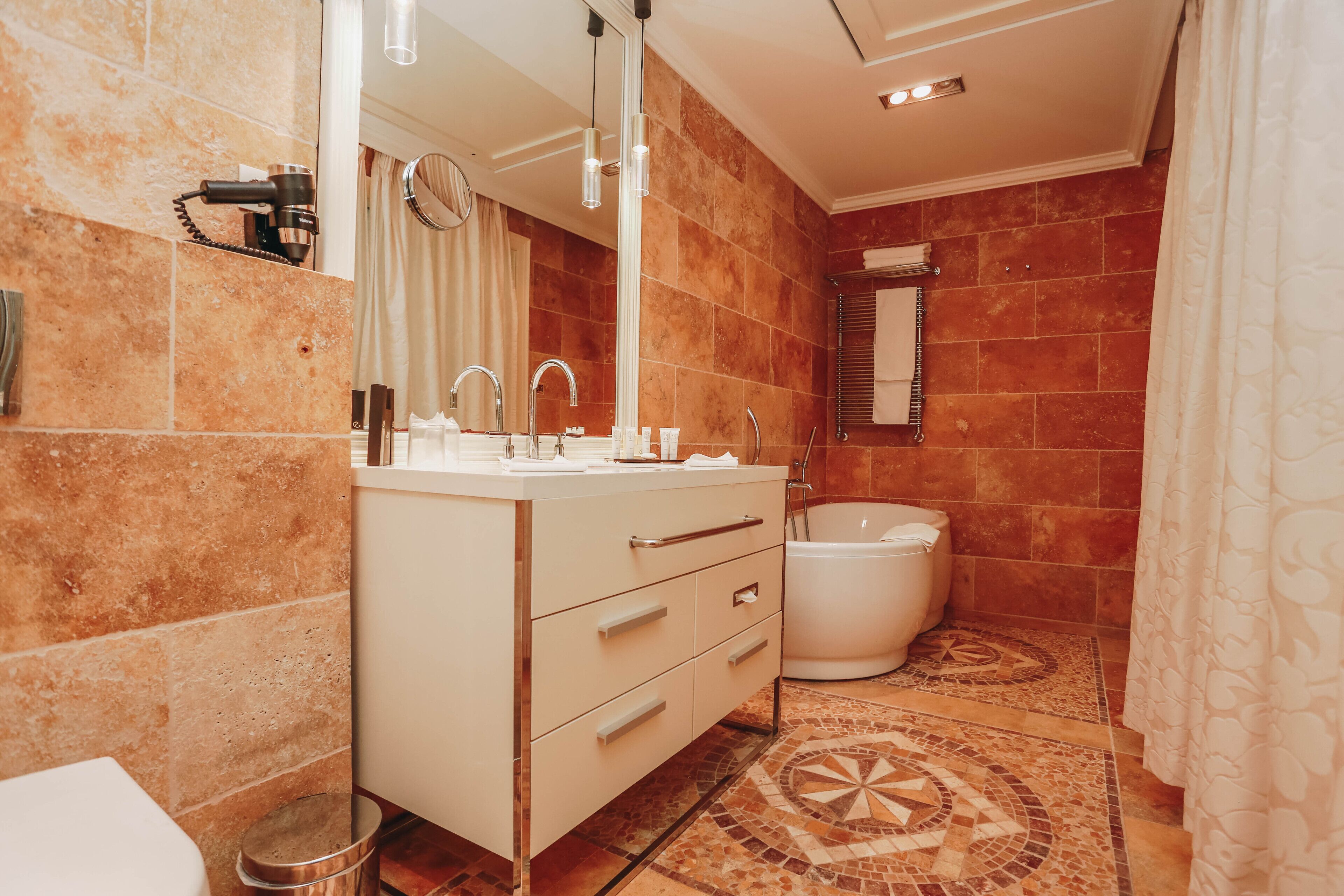 Une salle de bain avec un meuble-lavabo blanc, un grand miroir, une baignoire et des toilettes.