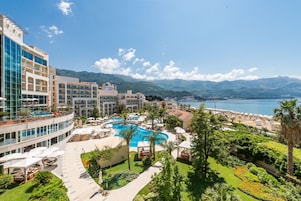 Un resort con una piscina grande, asientos al aire libre y vistas al mar.