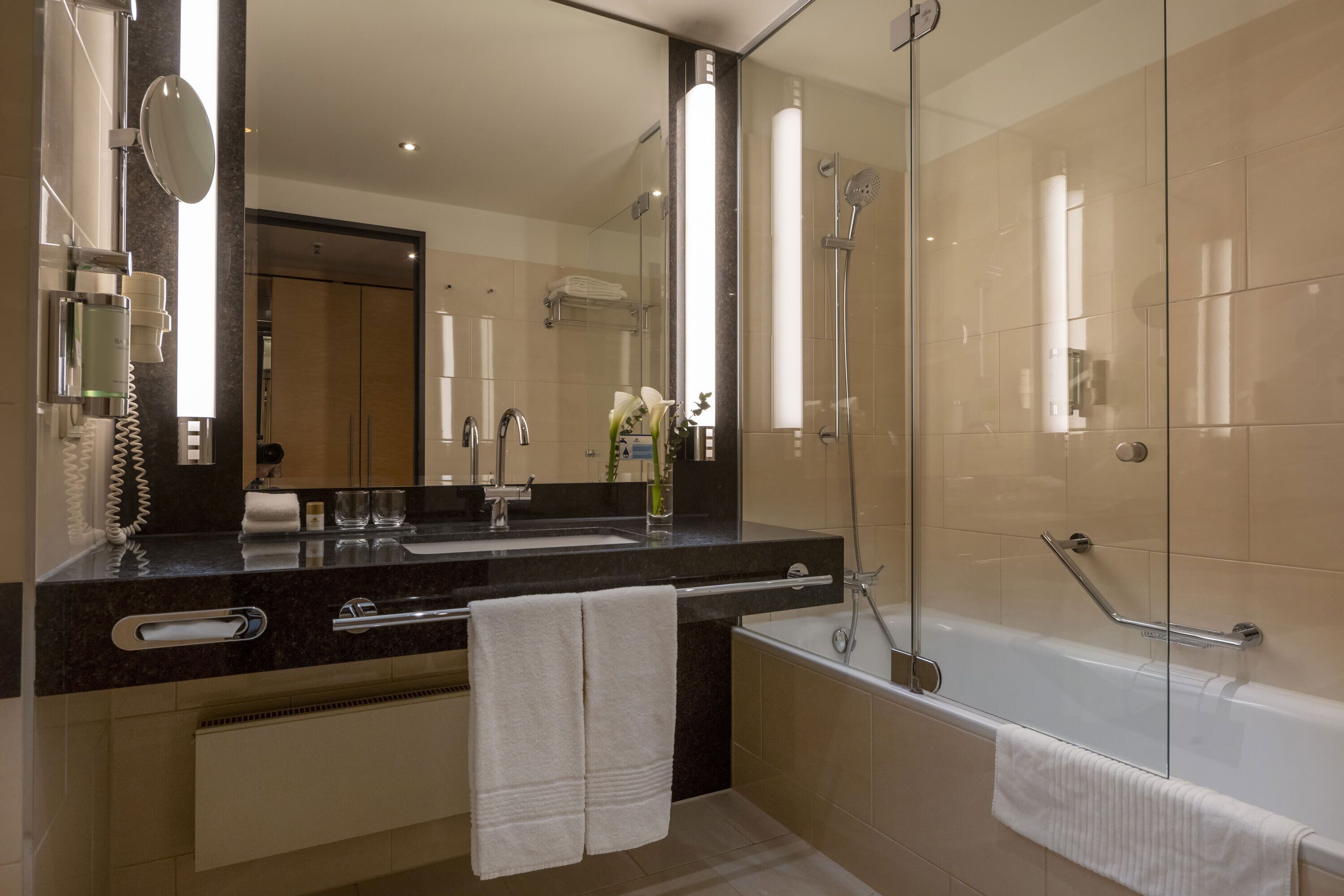 A modern bathroom with a large mirror, a bathtub, and a shower.