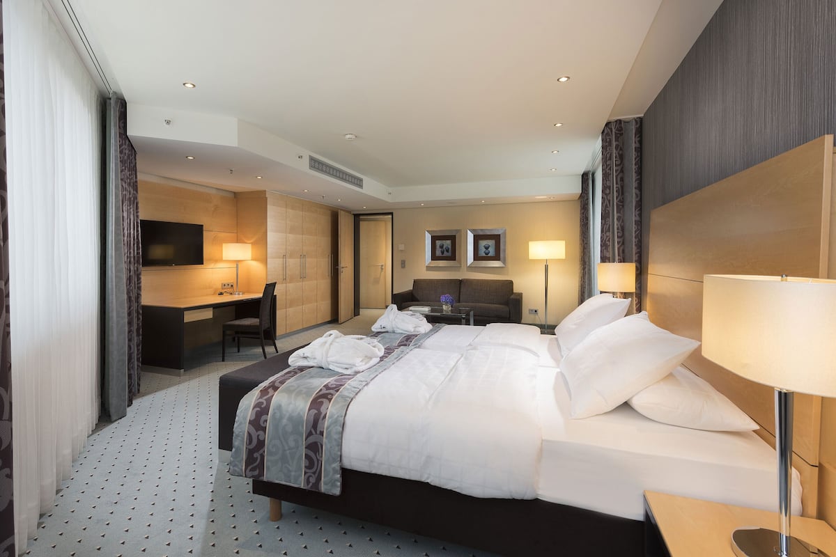 A hotel room with a large bed, a desk, a television, and a bathroom.