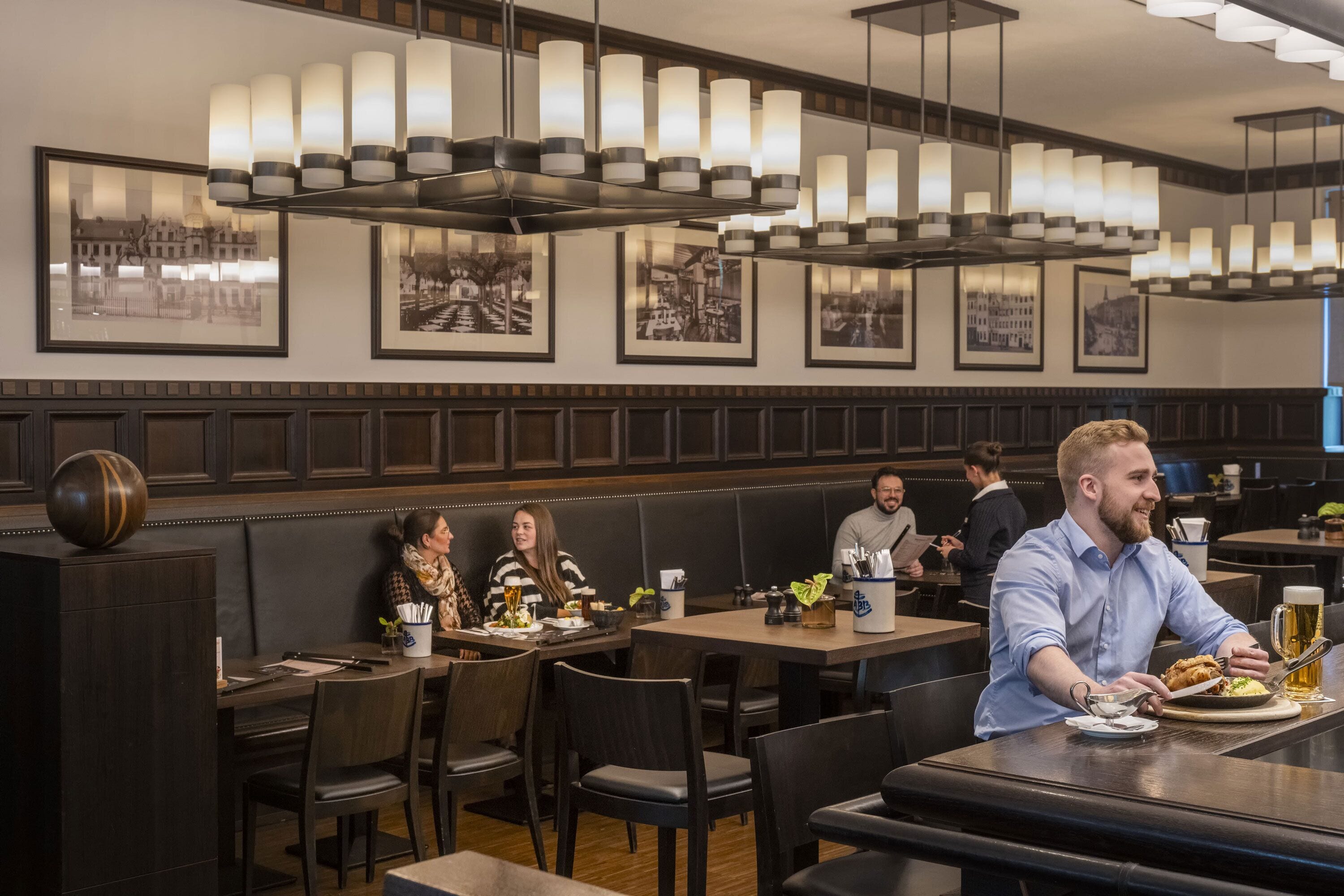 A restaurant with dark wood paneling, multiple tables, and framed black and white photographs on the walls.