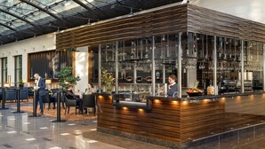 Un área de bar moderna con mostrador de madera, vitrinas de vidrio y asientos para los clientes.