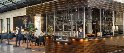 Un área de bar moderna con mostrador de madera, vitrinas de vidrio y asientos para los clientes.