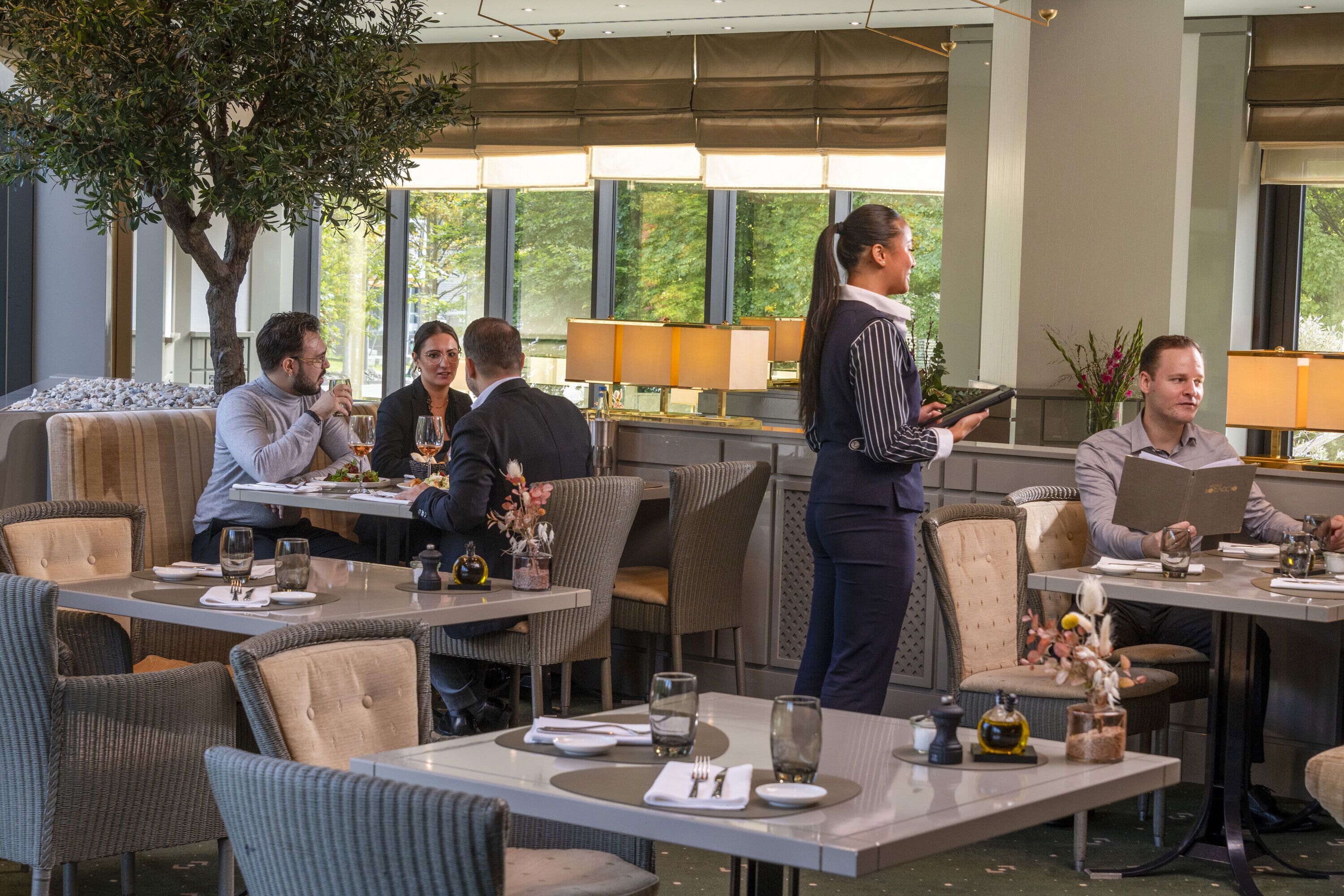 A restaurant with a waiter serving guests at a table.
