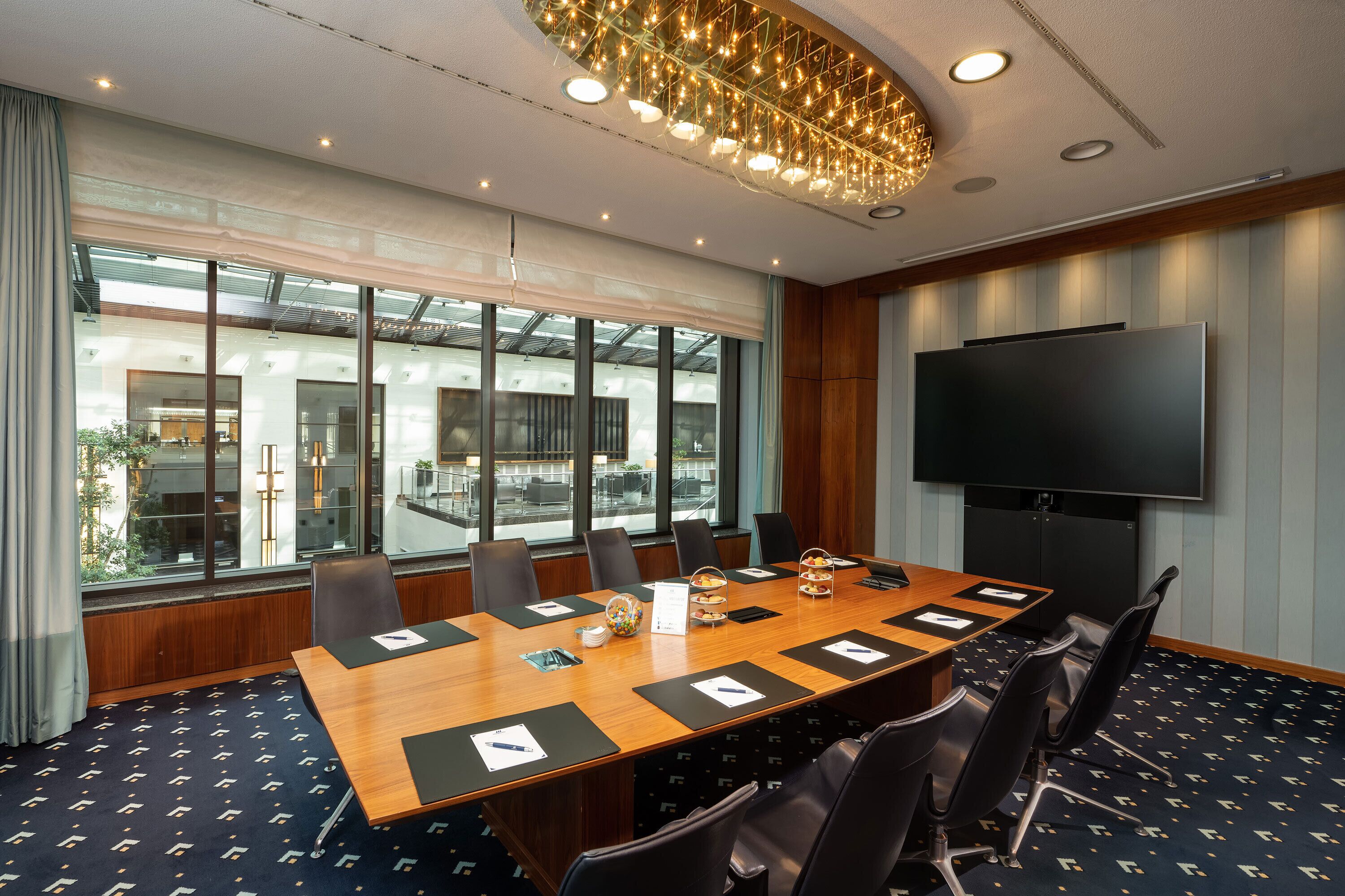 Une salle de conférence équipée d’une grande table, de chaises, d’un téléviseur et de grandes fenêtres.