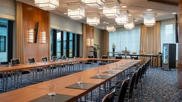 A conference room with long tables, chairs, and modern lighting fixtures.