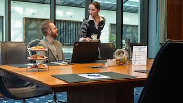 A conference room with a wooden table, two chairs, a laptop, a coffee cup, and a sign with motivational phrases.