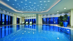 Una amplia piscina interior con un techo estrellado y vistas al cielo nocturno a través de las ventanas.