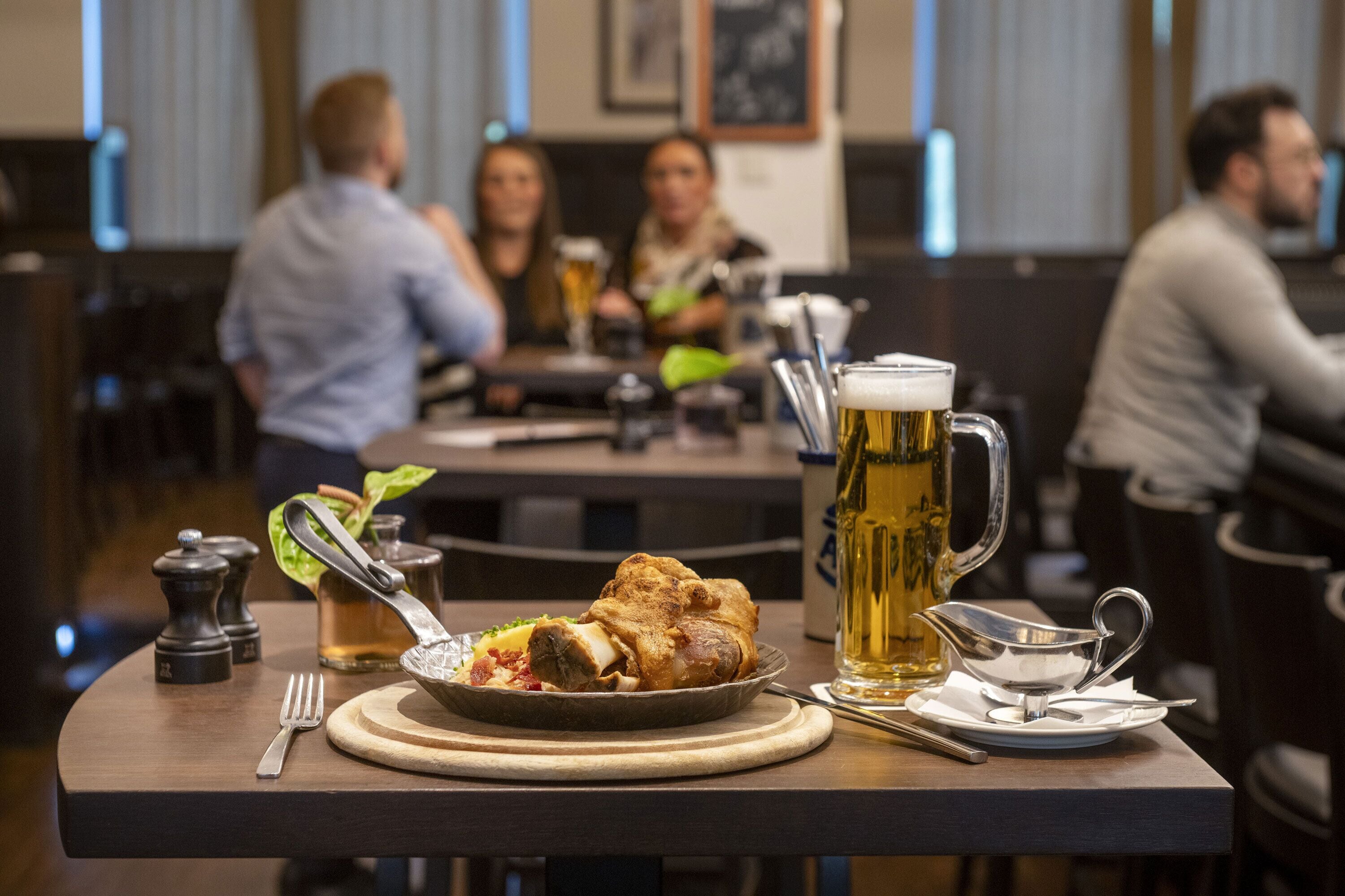 Ein Esstisch mit gebratenem Hähnchen, einem Bierkrug und einer silbernen Saucenschale.