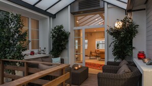 Un espacio al aire libre acogedor con mobiliario de mimbre, una terraza de madera y plantas en macetas.