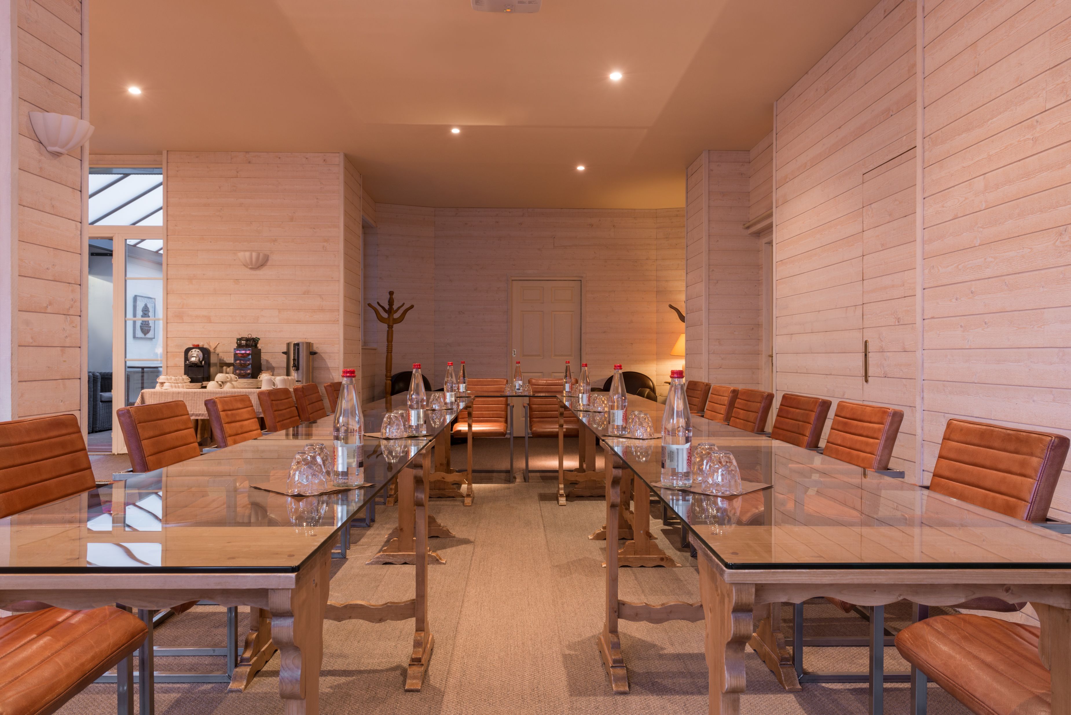 A conference room with a long table, brown leather chairs, and glassware.