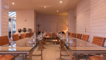 A conference room with a long table, brown leather chairs, and glassware.