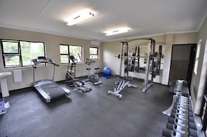 Une salle de sport équipée de tapis de course, d’appareils elliptiques, d’un vélo d’appartement, de poids libres et d’un ballon lesté.