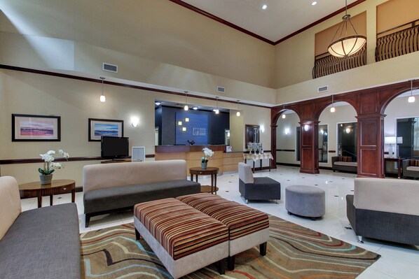 A spacious hotel lobby with a reception desk, seating area, and a balcony. - Holiday Inn Express & Suites Allentown West by IHG (Allentown)