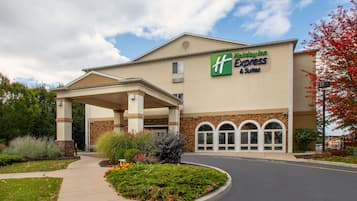 Edifício Holiday Inn Express com entrada coberta, jardim ajardinado e céu claro.