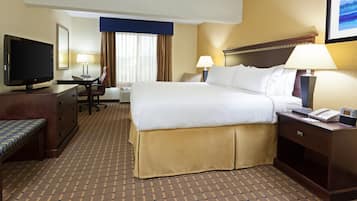 A hotel room with a bed, desk, chair, television, lamps, and a clock.