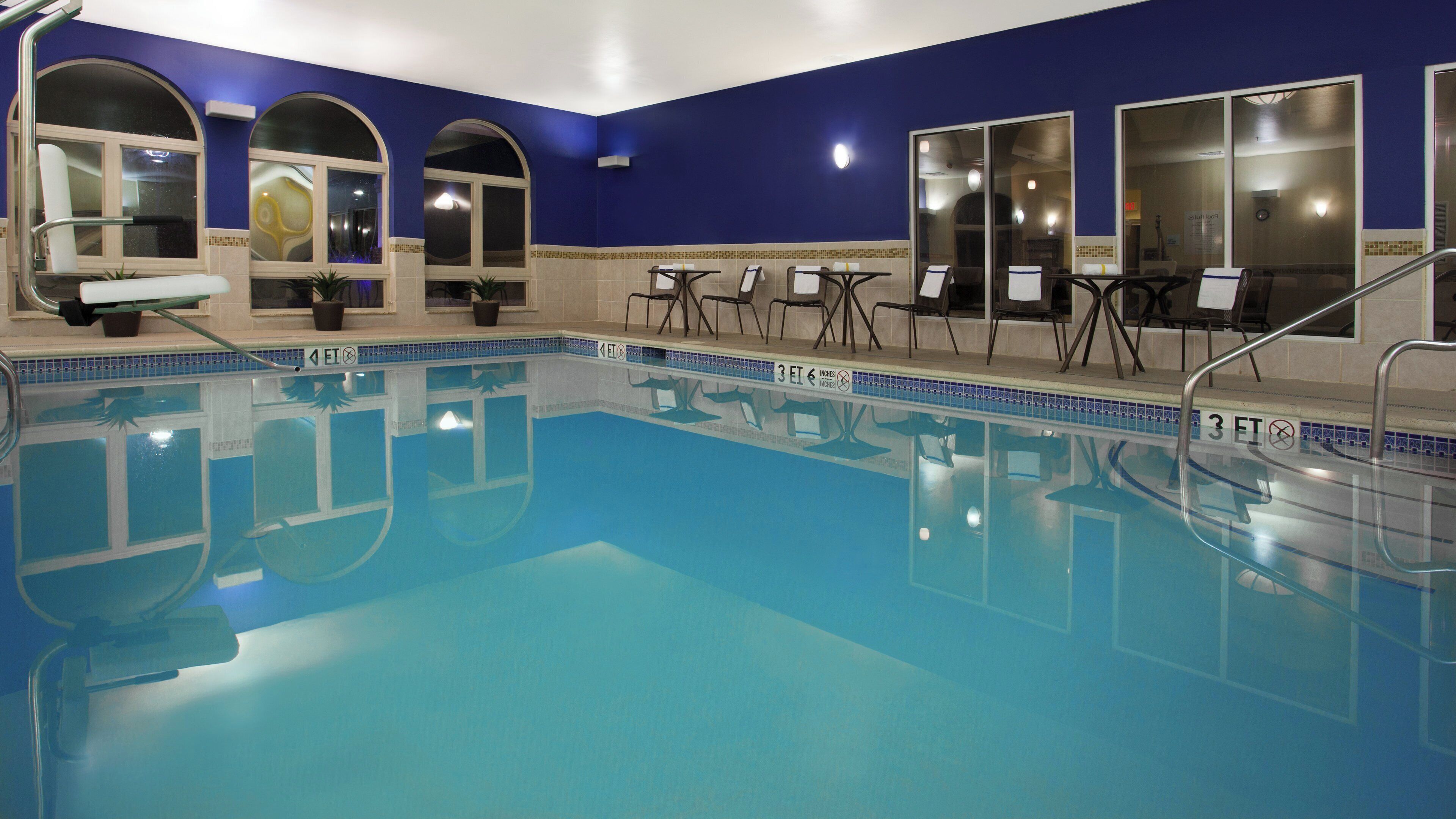 Una piscina interior con agua cristalina, rodeada de paredes azules y ventanas arqueadas.