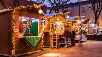 Una estructura de madera con toldo verde y una mesa, decorada con luces y guirnaldas.