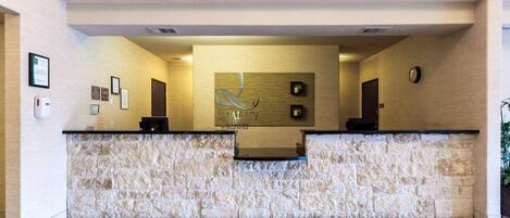 A reception desk with a stone facade, framed certificates on the wall, and a clock.