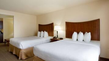 A hotel room with two beds, a nightstand, a lamp, and a telephone.