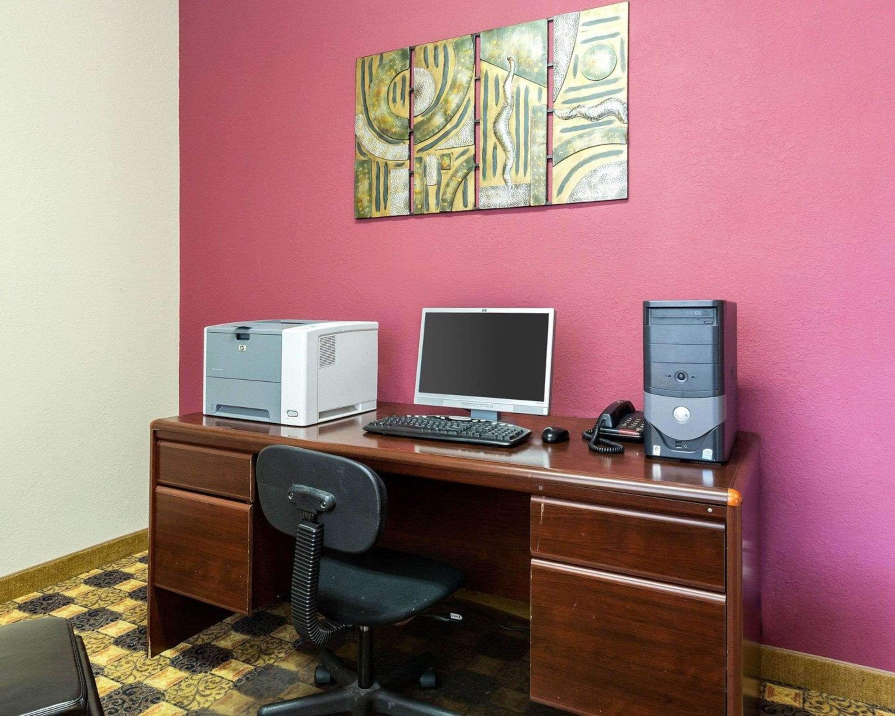 A wooden desk with a desktop computer, a printer, and a telephone.