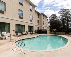 Una piscina al aire libre, sombrillas, sillones reclinables de piscina