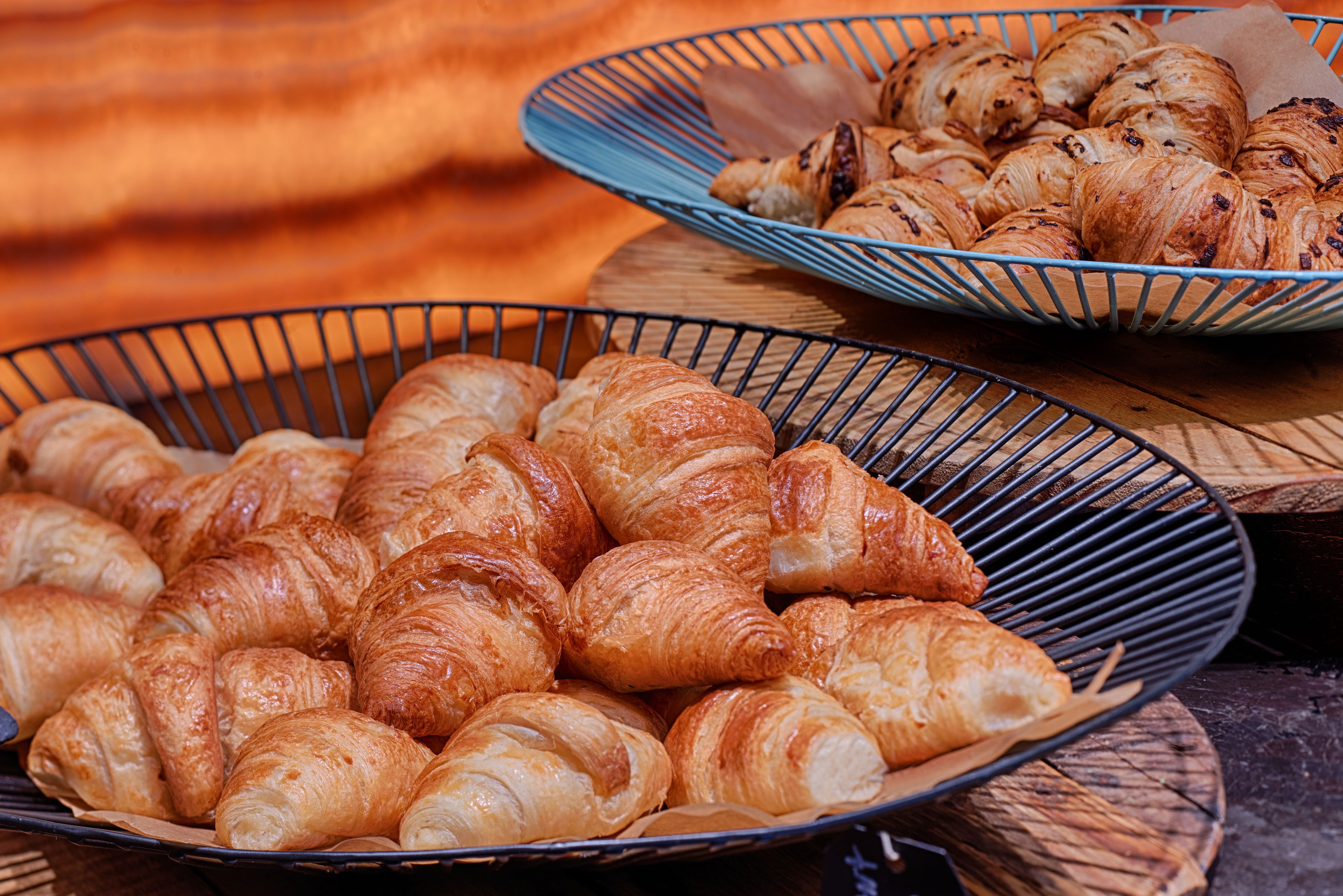 A tray of assorted pastries, including croissants and other baked goods, displayed on a wooden surface.