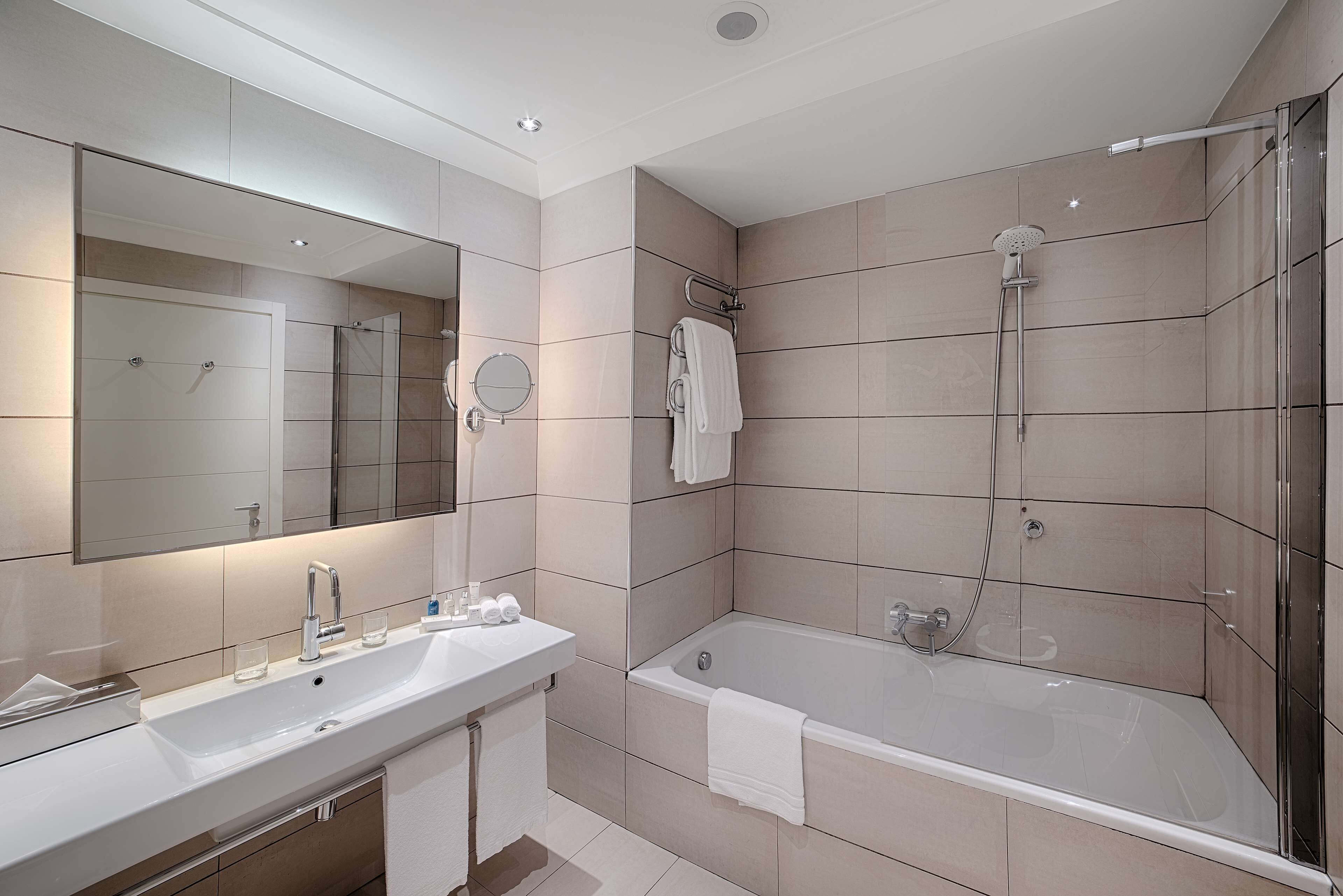 A modern bathroom with two sinks, a bathtub, and a shower.