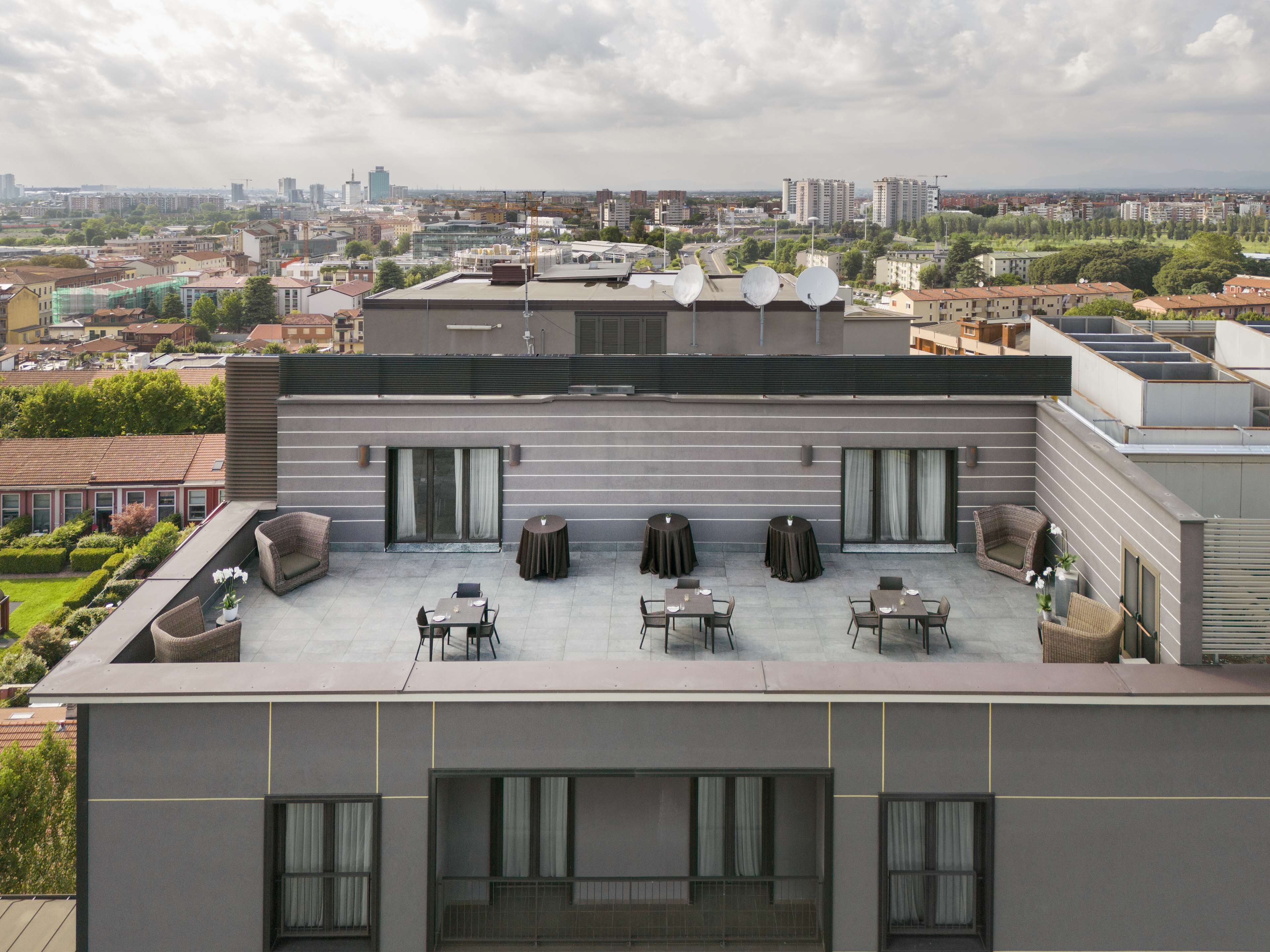 A rooftop terrace with outdoor seating, a view of the cityscape, and satellite dishes.