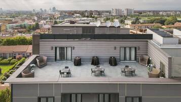 A rooftop terrace with outdoor seating, a view of the cityscape, and satellite dishes.