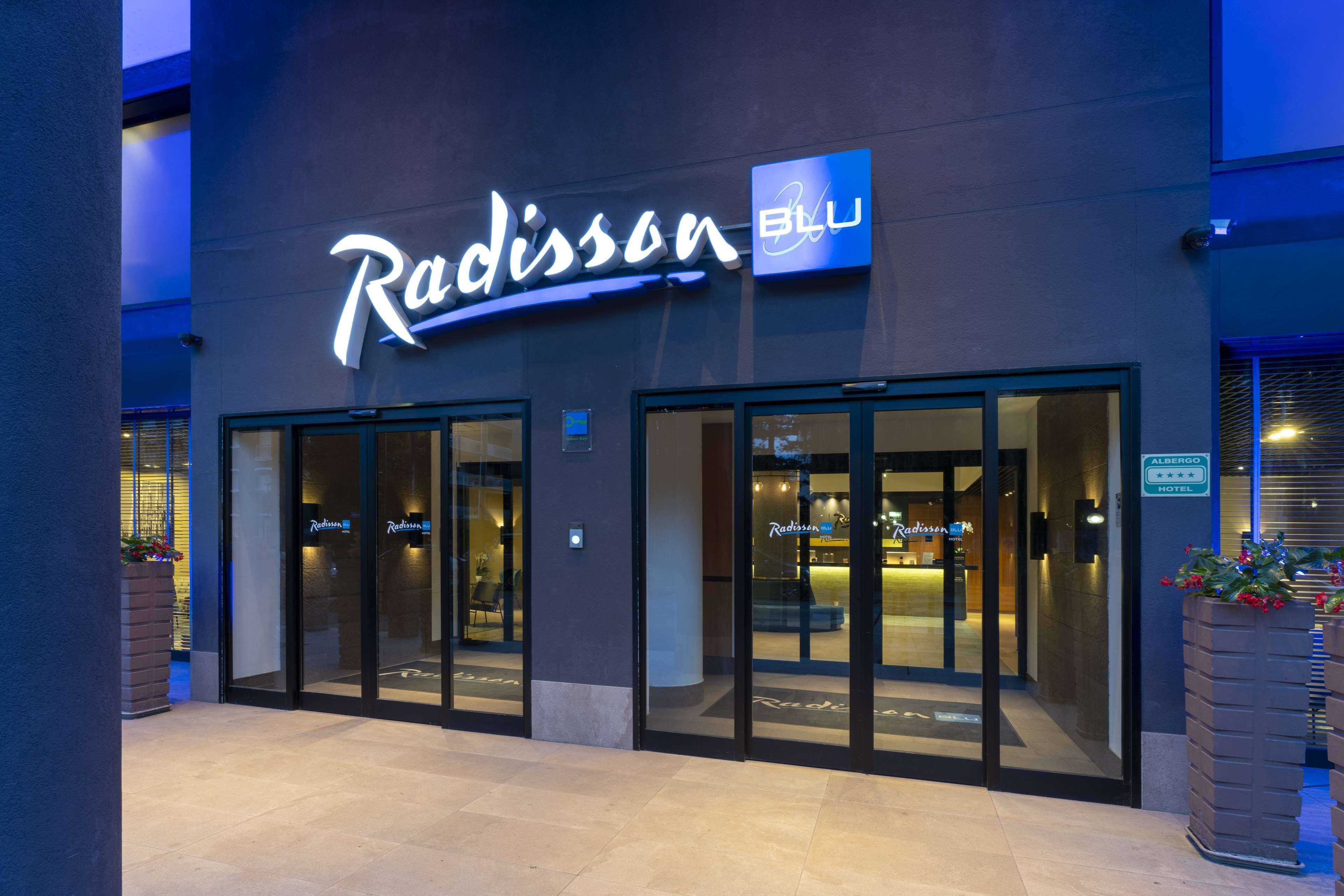 The exterior of Radisson Blu hotel with large glass doors and a well-lit entrance.