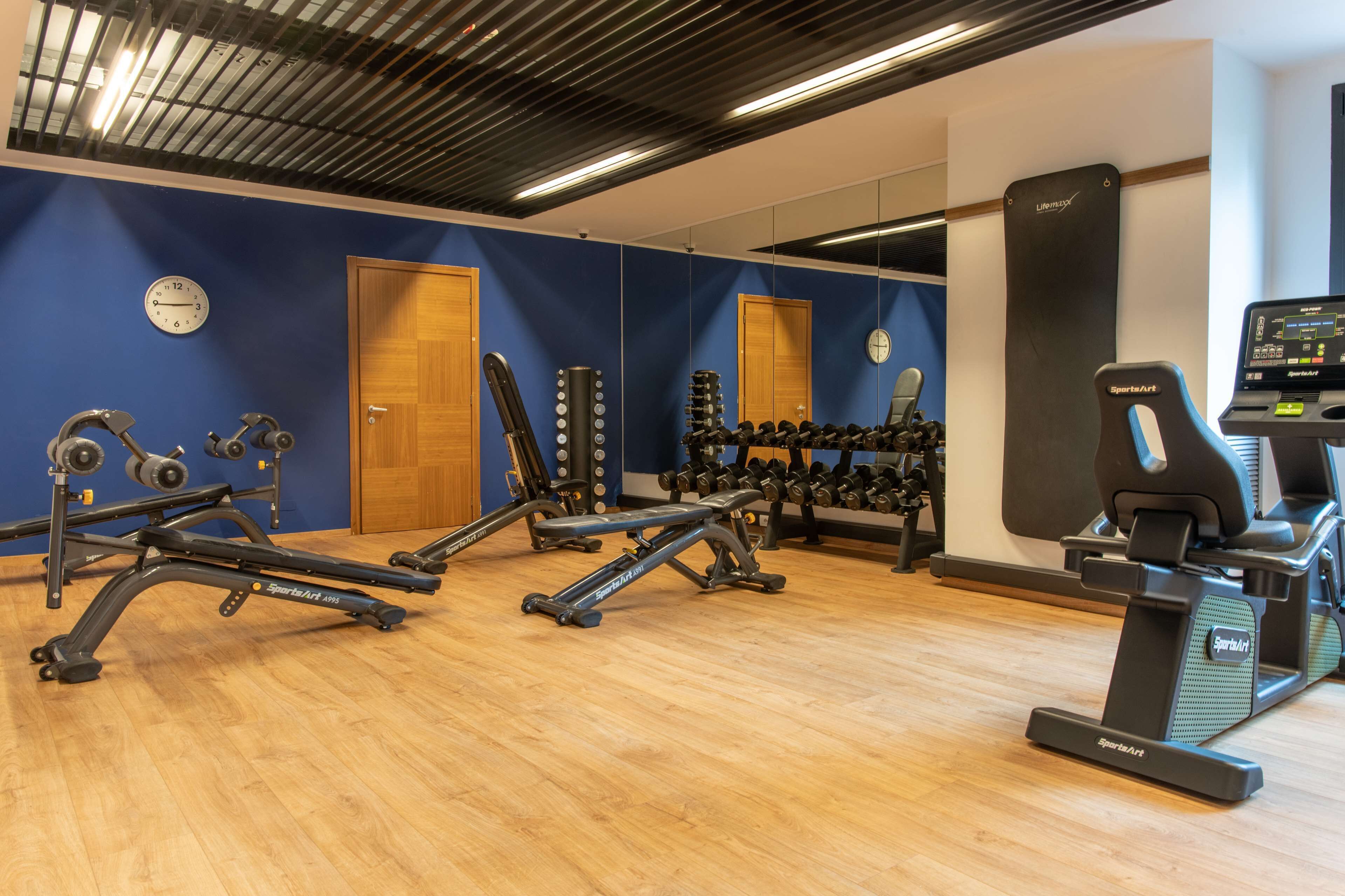 A gym with exercise equipment, a clock, and a punching bag.