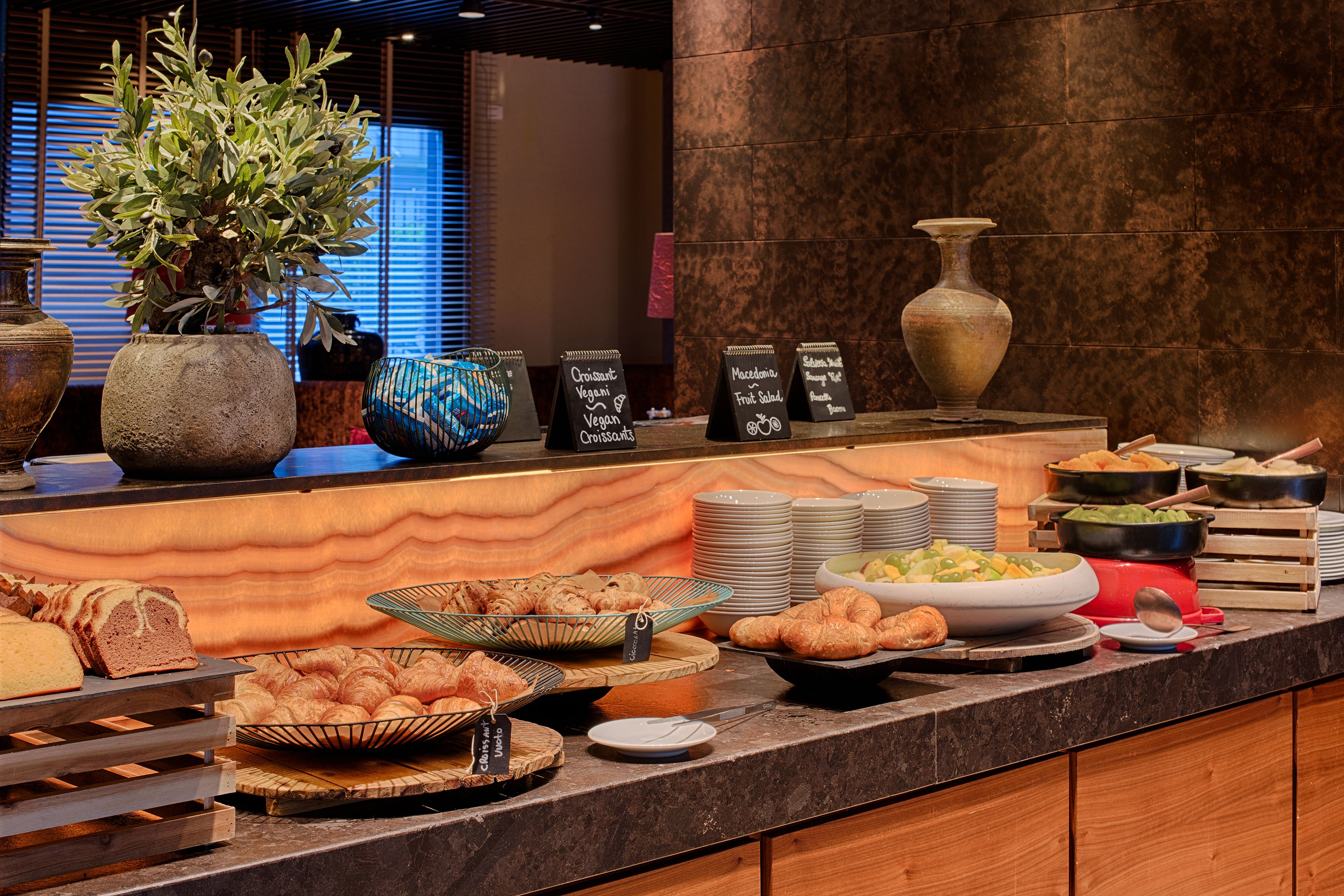A buffet with various food items, including croissants and a fruit salad.
